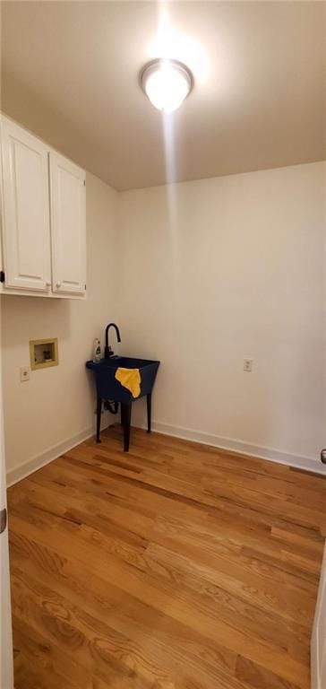 washroom featuring light wood-style flooring, hookup for a washing machine, cabinet space, and baseboards