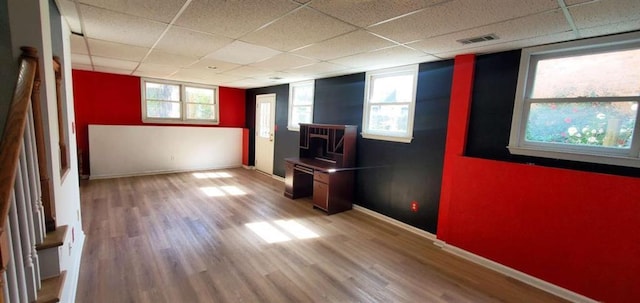 spare room featuring a paneled ceiling, visible vents, baseboards, and wood finished floors