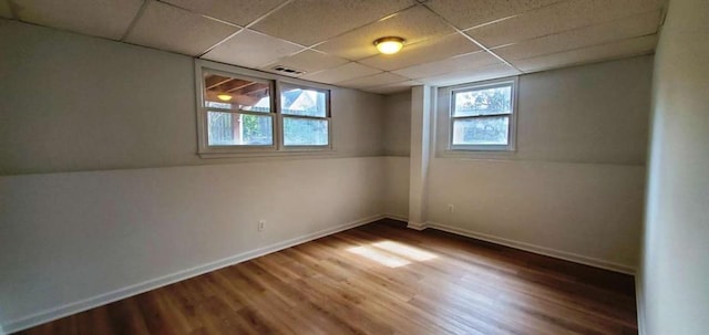 unfurnished room with a healthy amount of sunlight, a paneled ceiling, baseboards, and wood finished floors