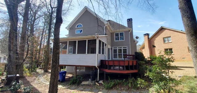 rear view of property with a sunroom and a chimney