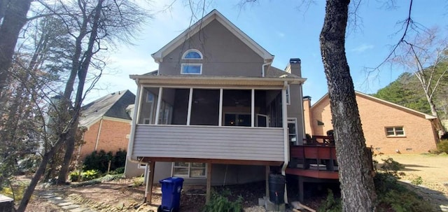 back of property featuring a deck, a sunroom, and a chimney