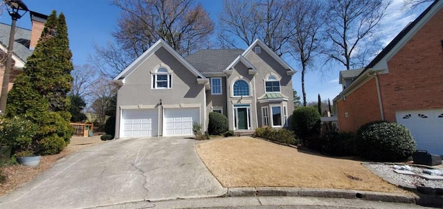 traditional-style home with concrete driveway, an attached garage, and stucco siding