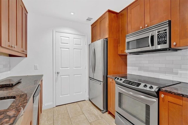 1075 Peachtree Walk NE Unit A421, Atlanta, GA 30309 - kitchen featuring stainless steel appliances, dark stone counters, brown cabinets, backsplash, and recessed lighting