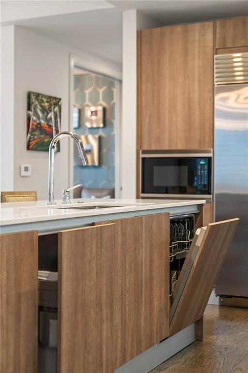 kitchen featuring built in appliances, dark hardwood / wood-style flooring, and sink