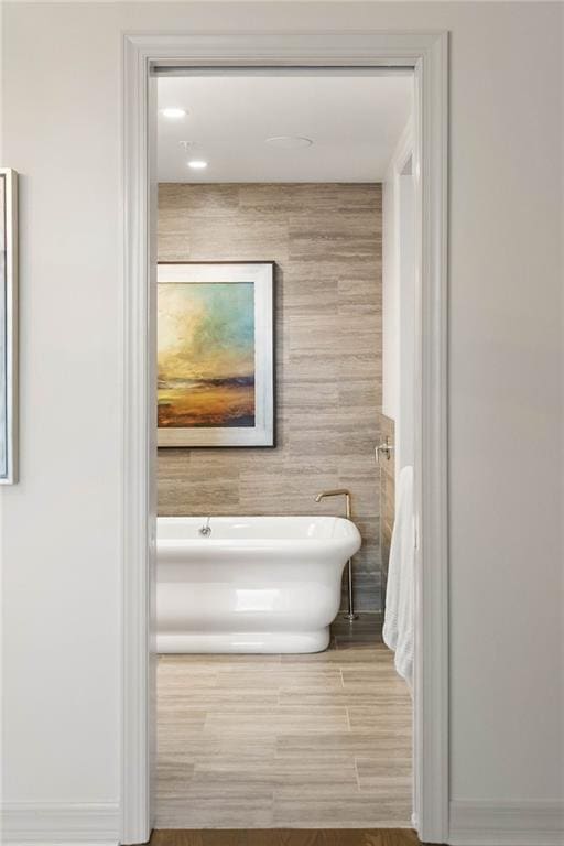 bathroom featuring a bathtub, wood-type flooring, and tile walls