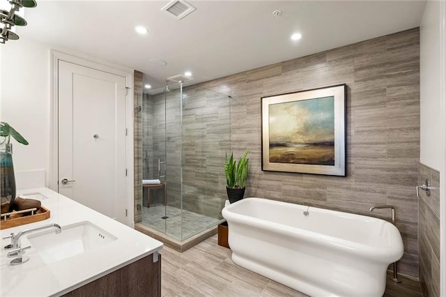 bathroom with hardwood / wood-style flooring, vanity, tile walls, and shower with separate bathtub