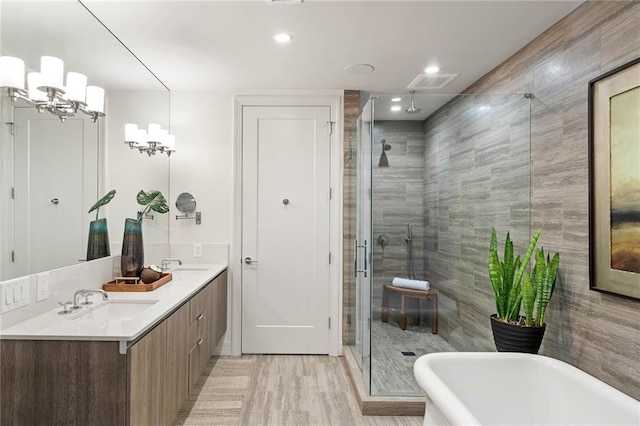 bathroom with vanity, separate shower and tub, wood-type flooring, tile walls, and a notable chandelier