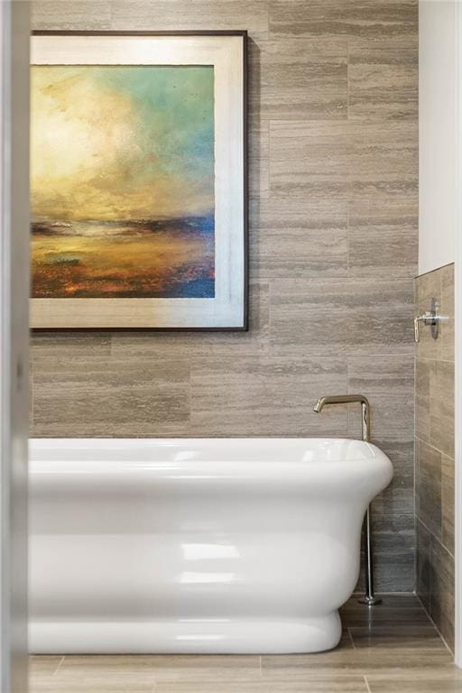 bathroom featuring a tub to relax in and tile walls