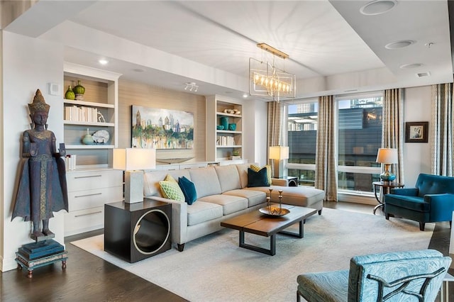 living room with light wood-type flooring, built in features, and a notable chandelier