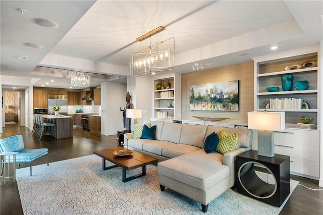 living room with dark hardwood / wood-style flooring, built in features, and a notable chandelier