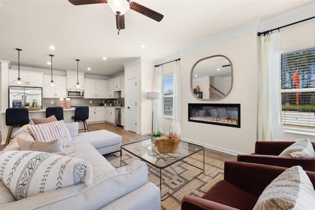 living room featuring crown molding, ceiling fan, and light hardwood / wood-style floors