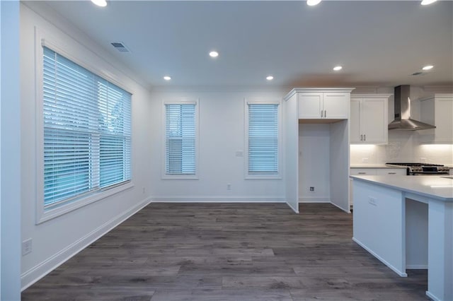 kitchen with crown molding, dark hardwood / wood-style flooring, decorative backsplash, wall chimney exhaust hood, and white cabinetry