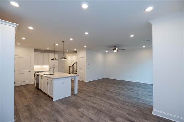 kitchen with sink, white cabinetry, an island with sink, hanging light fixtures, and dark wood-type flooring