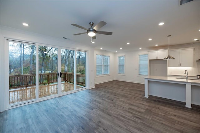 unfurnished living room featuring ceiling fan, sink, and dark hardwood / wood-style floors