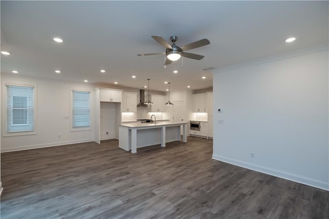 kitchen featuring a center island with sink, hanging light fixtures, dark hardwood / wood-style floors, white cabinetry, and wall chimney range hood