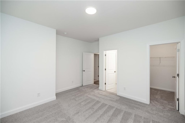 unfurnished bedroom featuring a closet, a spacious closet, and light carpet