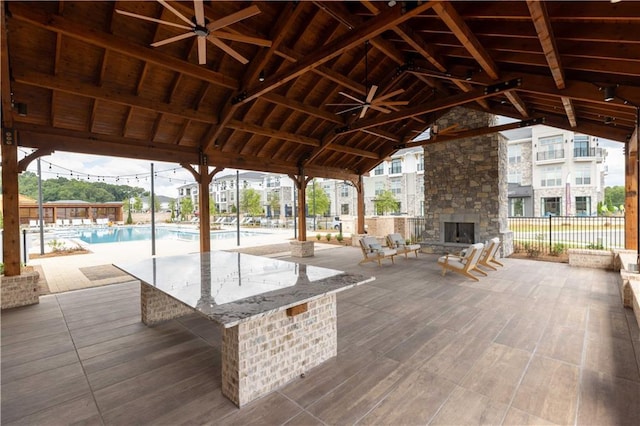 exterior space with a gazebo, an outdoor stone fireplace, ceiling fan, and a community pool