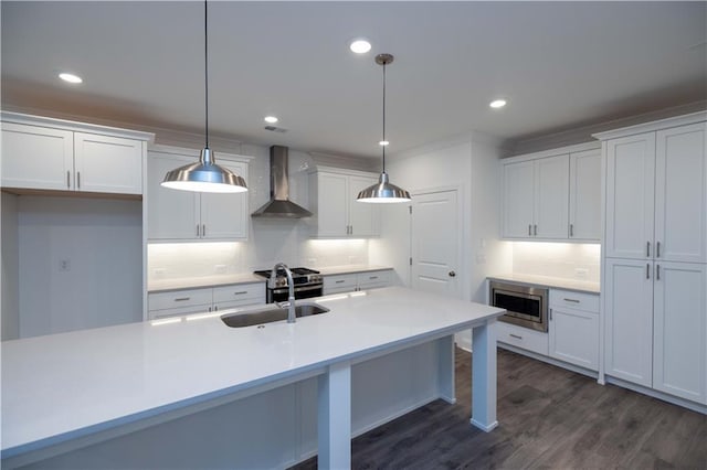 kitchen featuring appliances with stainless steel finishes, white cabinets, hanging light fixtures, and wall chimney exhaust hood