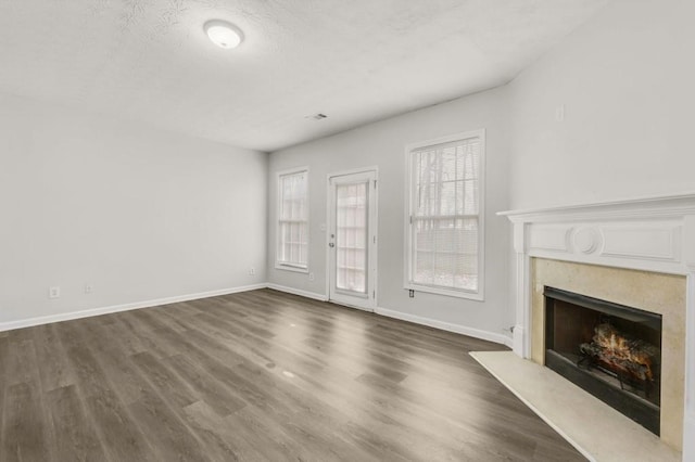 unfurnished living room featuring a premium fireplace, dark hardwood / wood-style flooring, and a textured ceiling