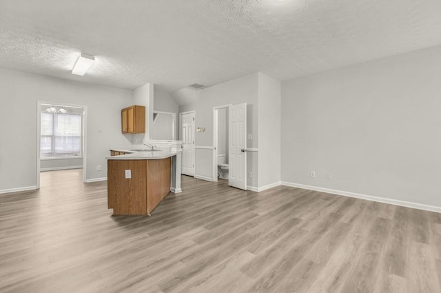 kitchen featuring kitchen peninsula, sink, light hardwood / wood-style flooring, and a textured ceiling