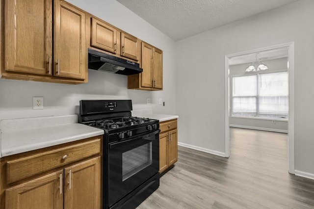 kitchen with black range with gas cooktop, light hardwood / wood-style flooring, a textured ceiling, and an inviting chandelier