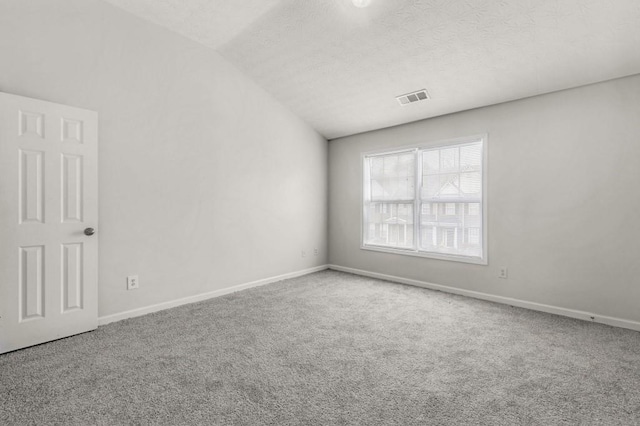 spare room with lofted ceiling, carpet floors, and a textured ceiling