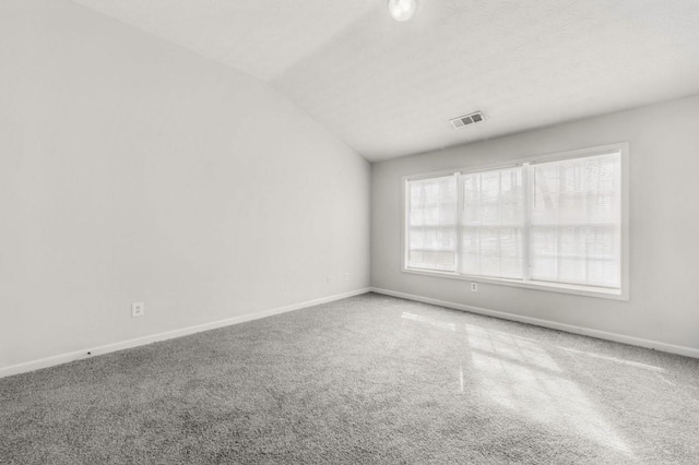 carpeted empty room featuring lofted ceiling