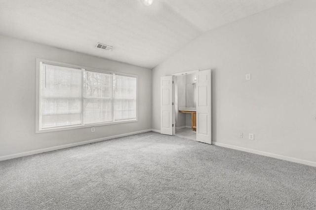 unfurnished bedroom with vaulted ceiling and carpet flooring