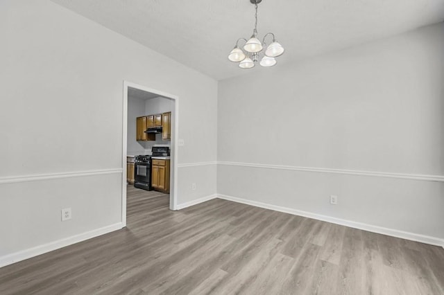 unfurnished dining area with a notable chandelier and wood-type flooring