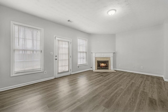 unfurnished living room with dark wood-type flooring, a wealth of natural light, and a textured ceiling