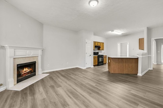 unfurnished living room featuring wood-type flooring, a premium fireplace, and a textured ceiling