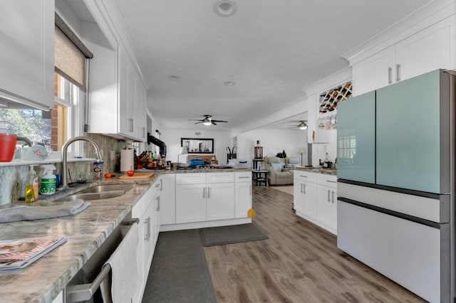 kitchen with a peninsula, white cabinetry, a sink, and freestanding refrigerator