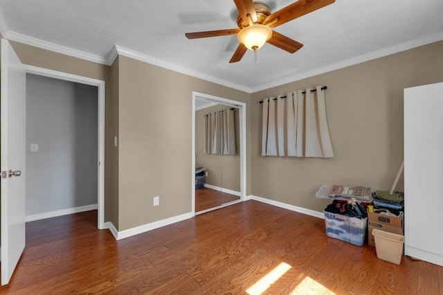 unfurnished bedroom featuring baseboards, a closet, ornamental molding, and wood finished floors