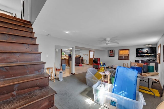 living room featuring ceiling fan and stairs