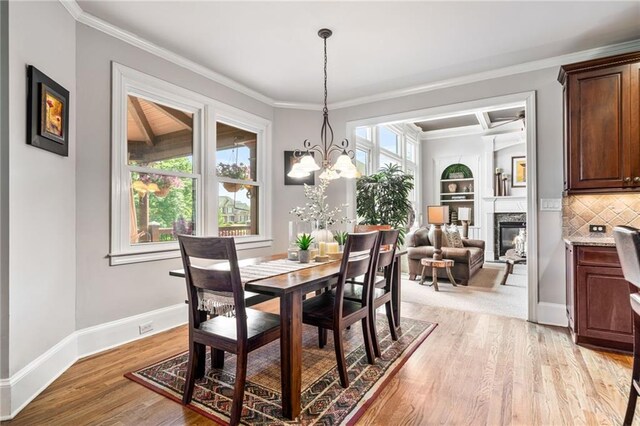 living room featuring an inviting chandelier, crown molding, and wainscoting