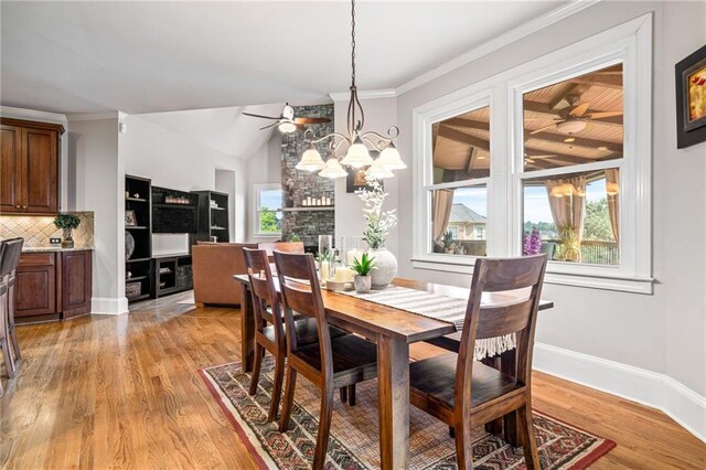 kitchen featuring under cabinet range hood, a notable chandelier, ornamental molding, a breakfast bar, and stainless steel appliances
