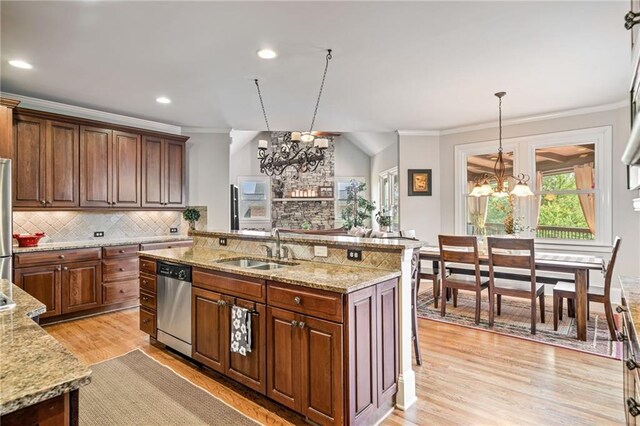 kitchen with a sink, stainless steel appliances, open floor plan, light wood-type flooring, and a center island with sink