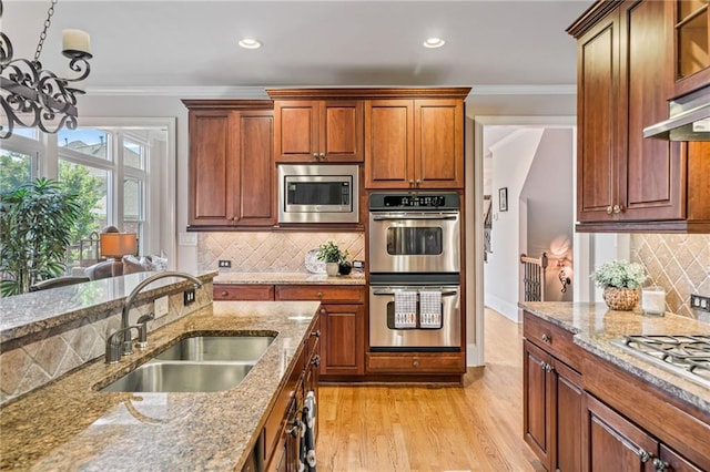 kitchen featuring a sink, appliances with stainless steel finishes, ornamental molding, and a chandelier