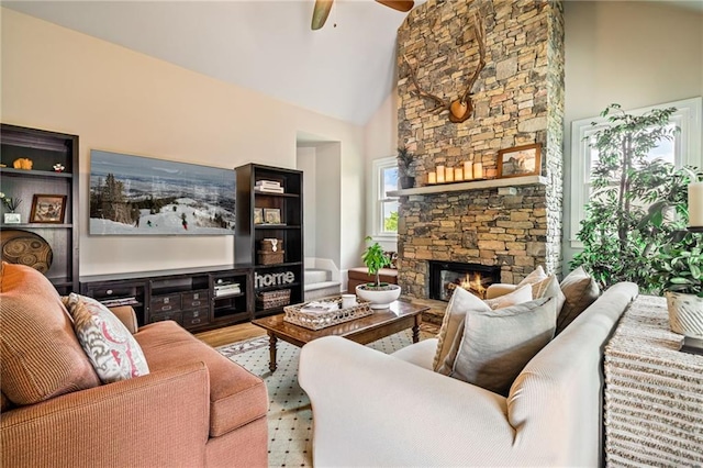 living area featuring high vaulted ceiling, a fireplace, a ceiling fan, and wood finished floors