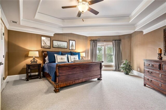 carpeted bedroom featuring baseboards, ornamental molding, ceiling fan, and a tray ceiling