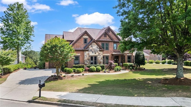 view of front of property with a front yard, driveway, and stone siding