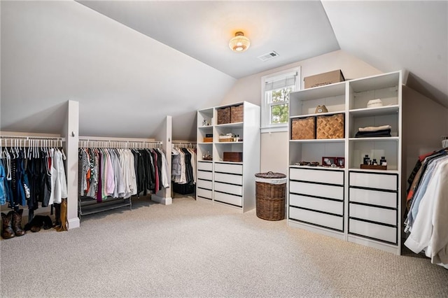 walk in closet with visible vents, carpet flooring, and lofted ceiling