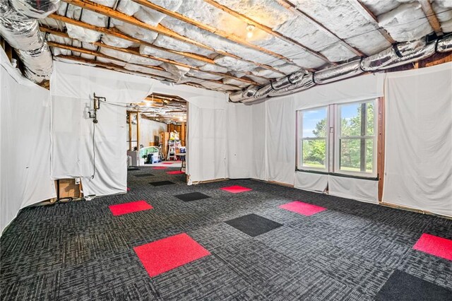 office area with a ceiling fan, visible vents, vaulted ceiling, baseboards, and light carpet