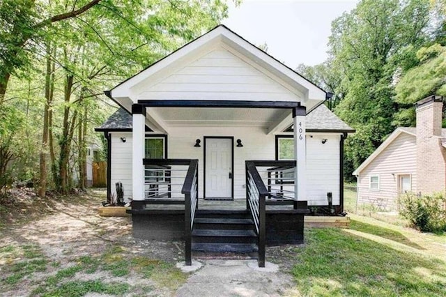 bungalow-style home featuring covered porch and a front yard