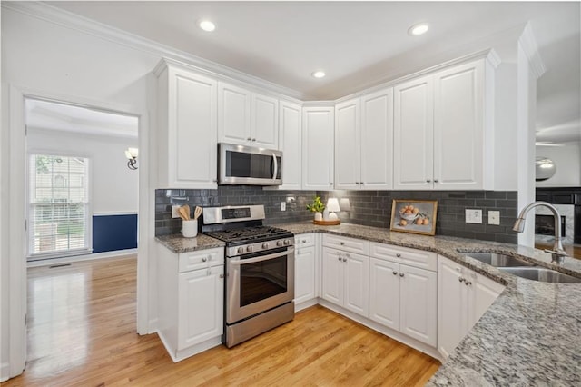 2350 Twelvestones Dr, Roswell, GA 30076 - kitchen featuring stainless steel appliances, a sink, crown molding, white cabinets, and light wood-style flooring