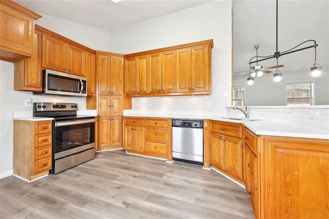 kitchen featuring stainless steel appliances, light wood finished floors, a sink, and light countertops