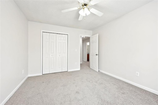 unfurnished bedroom with a textured ceiling, carpet flooring, a ceiling fan, baseboards, and a closet