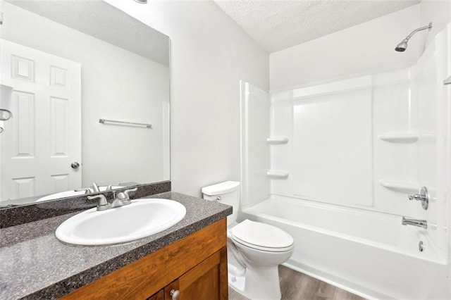 bathroom with toilet, wood finished floors, a textured ceiling, vanity, and shower / bathing tub combination