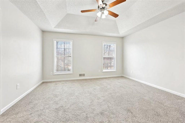 empty room with a wealth of natural light, a raised ceiling, and visible vents