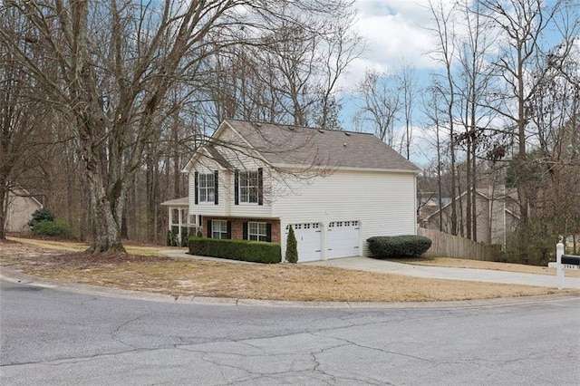 view of home's exterior featuring a garage, brick siding, driveway, and fence